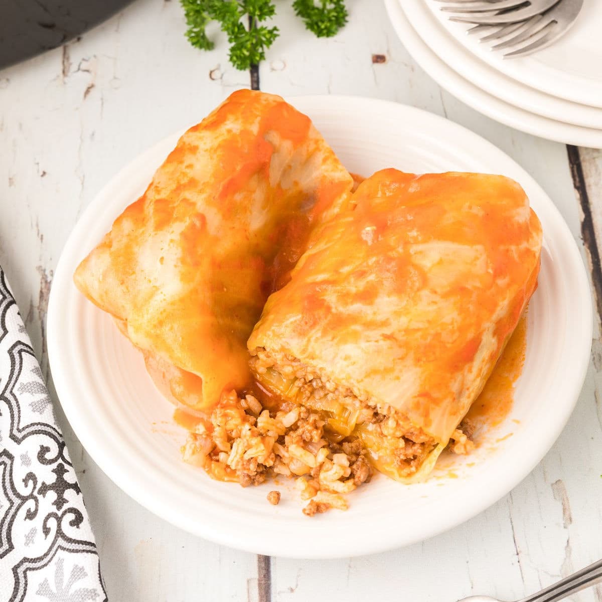 Overhead view of cabbage rolls cut open on a white plate.