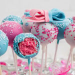 A blue cake pop with white decorations opened up to see the pink inside of the pop.