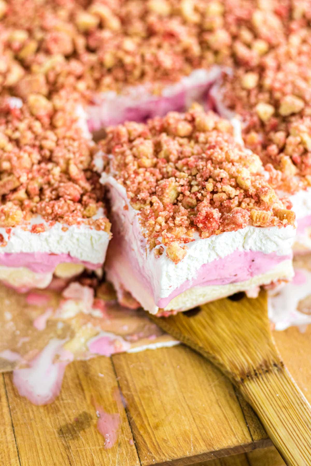 A serving of ice cream cake being removed from the cutting board.