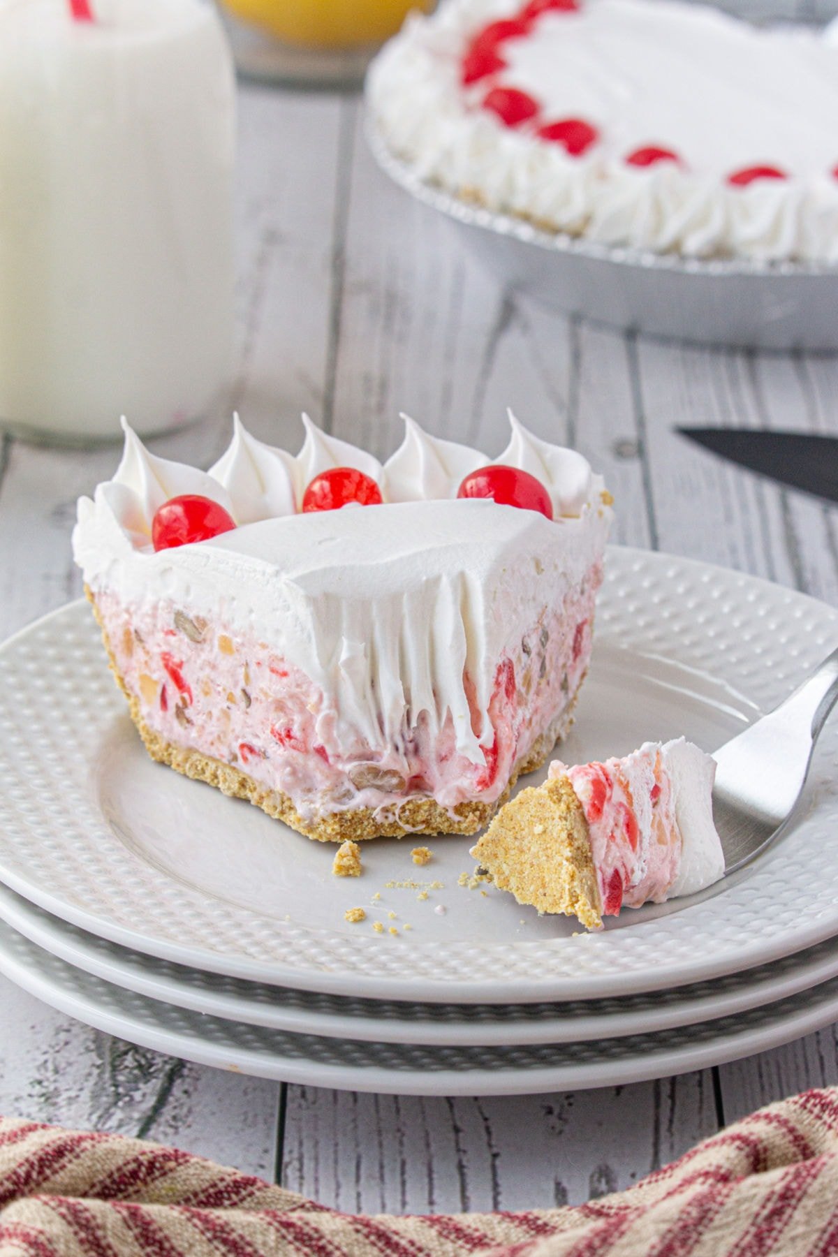 A slice of pie on a stack of white dishes with a fork next to the pie.