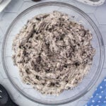 Overhead view of cookies and cream cake filling in a glass bowl.