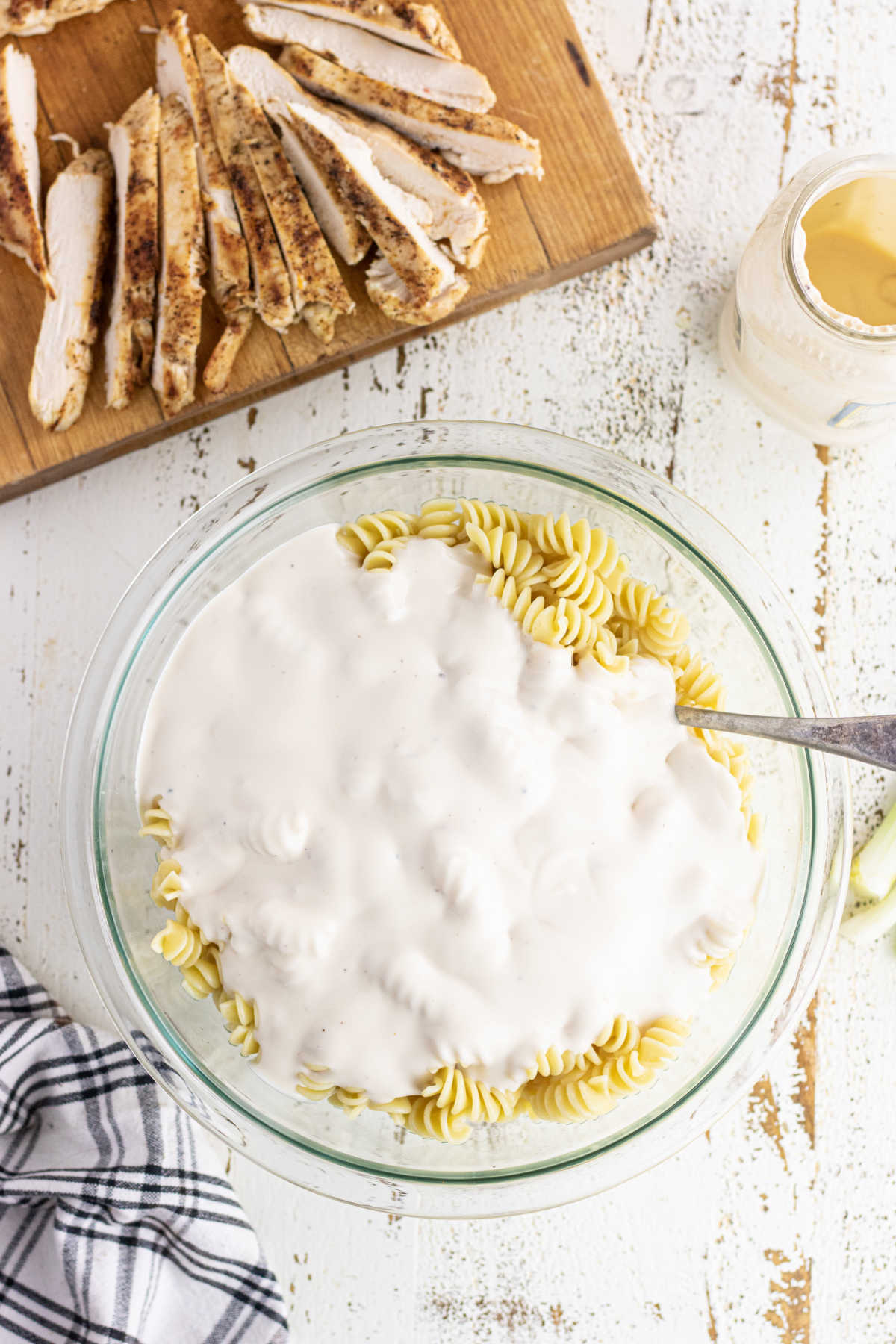 Alfredo sauce being stirred into cooked pasta.