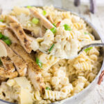 A serving spoon lifting a serving of chicken alfredo from the dish.