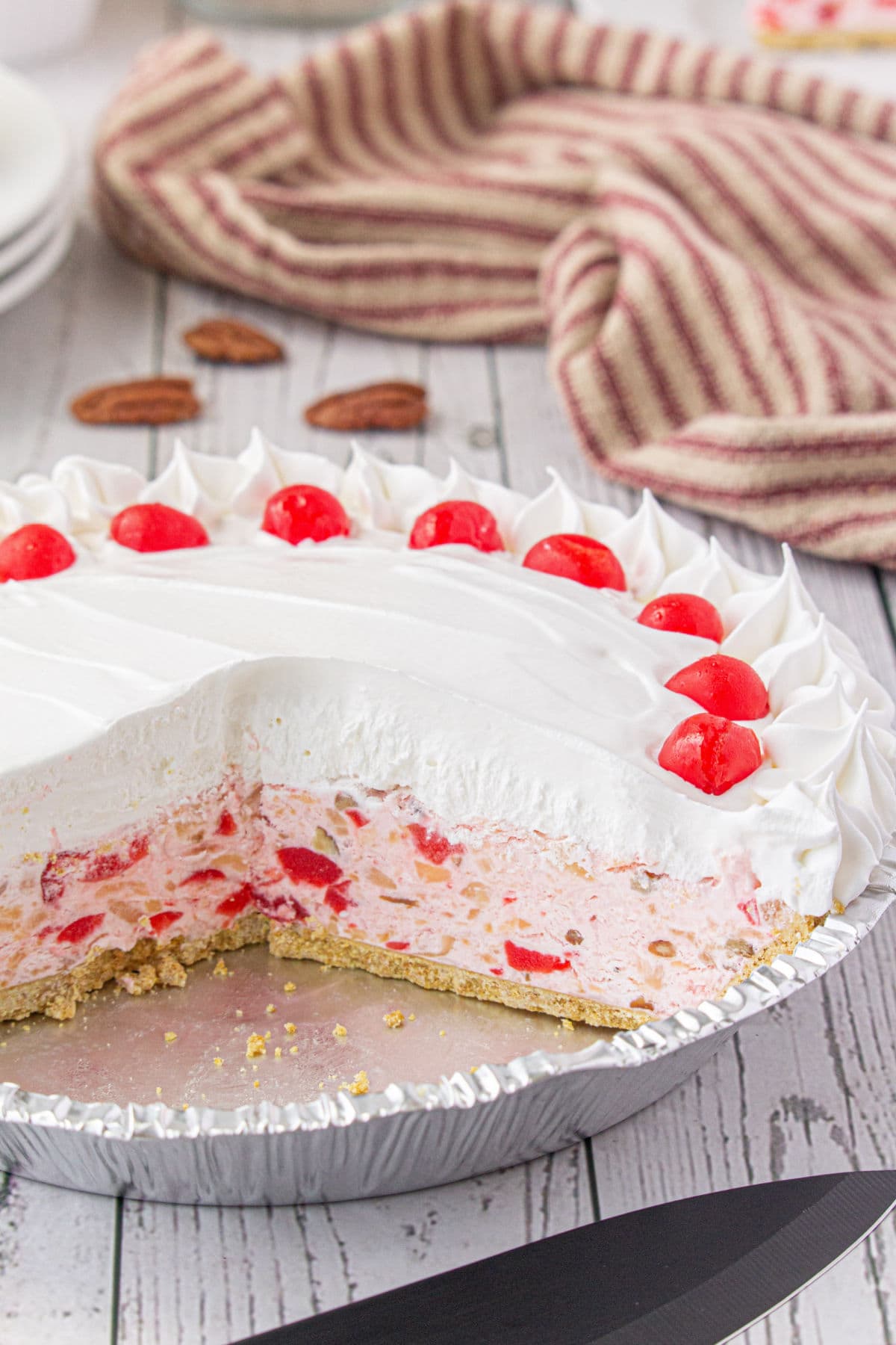 Whole pie with a slice removed to show the creamy layers of filling and whipped cream topping.