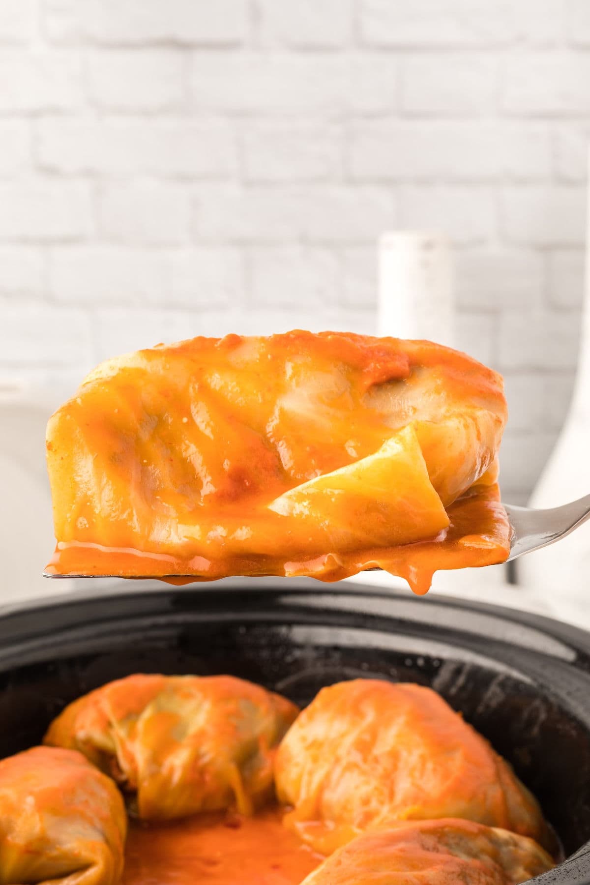 Finished cabbage roll being spooned out of the slow cooker.