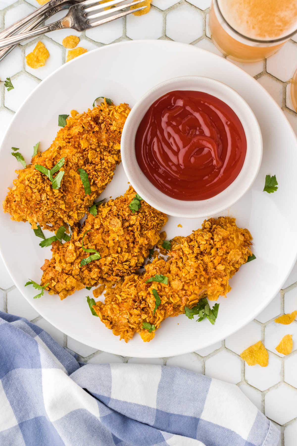 Overhead view of crispy chicken tenders on a white plate.