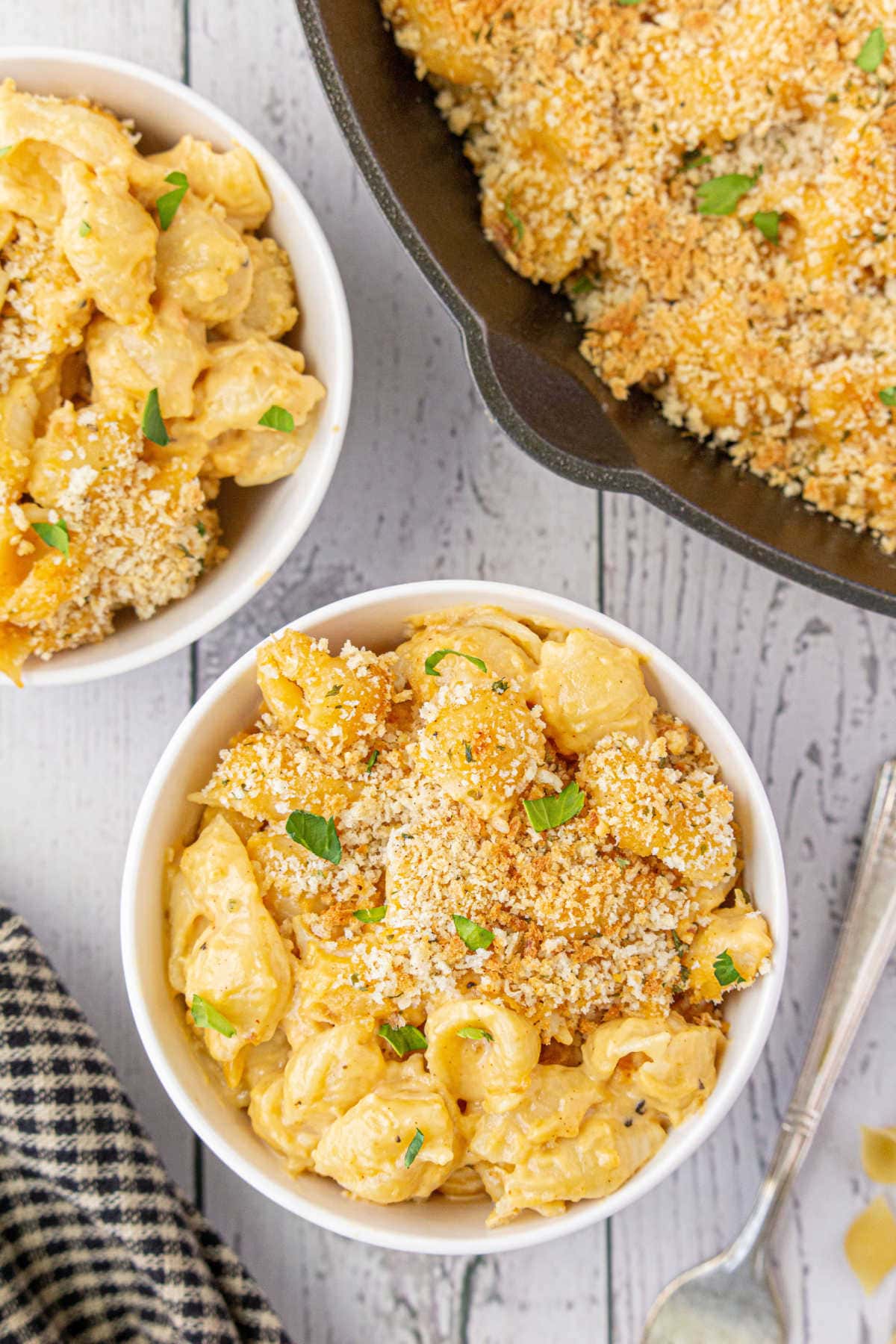 Bowls of beer macaroni and cheese next to a skillet.