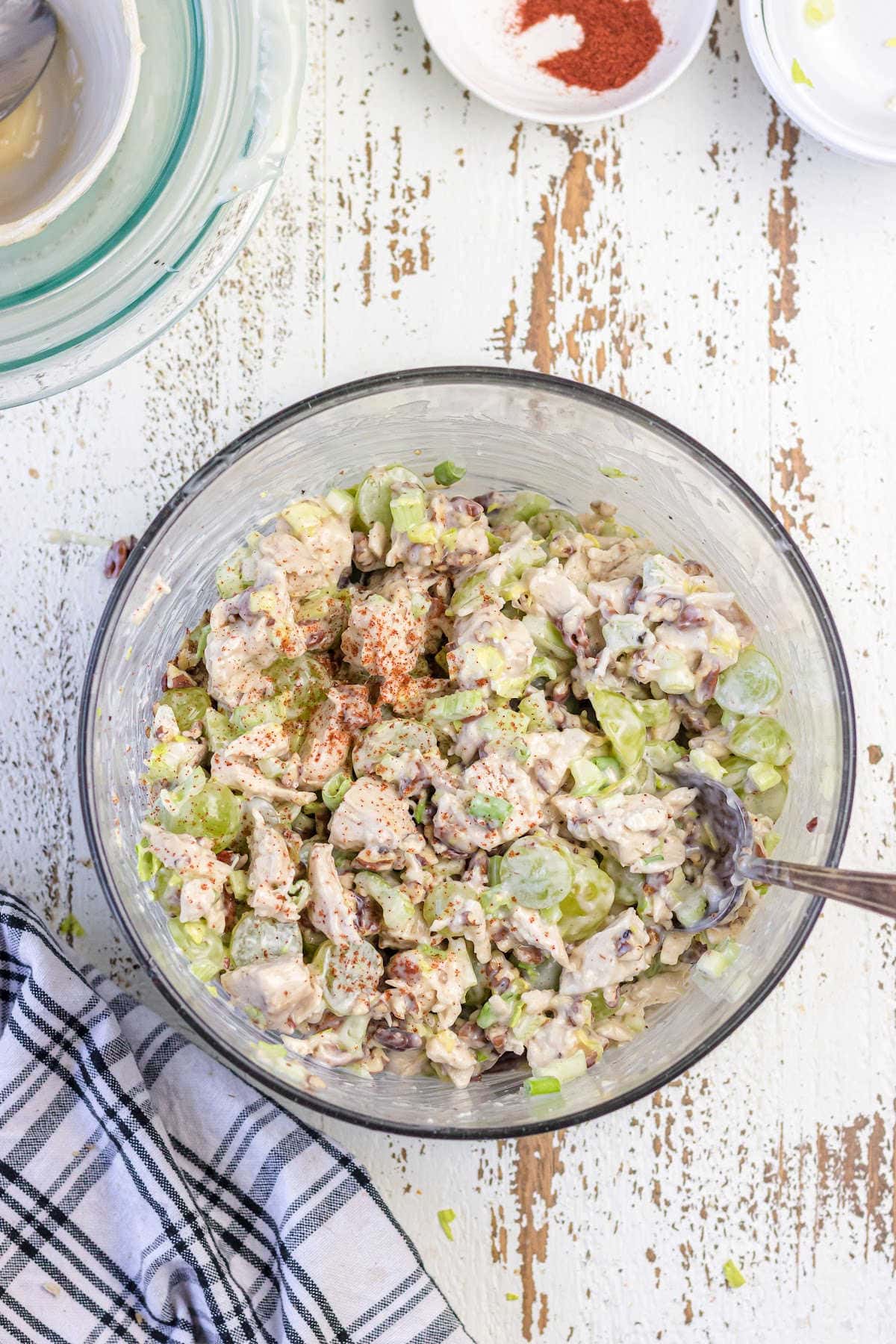 A bowl of creamy chicken salad with grapes on a white table.