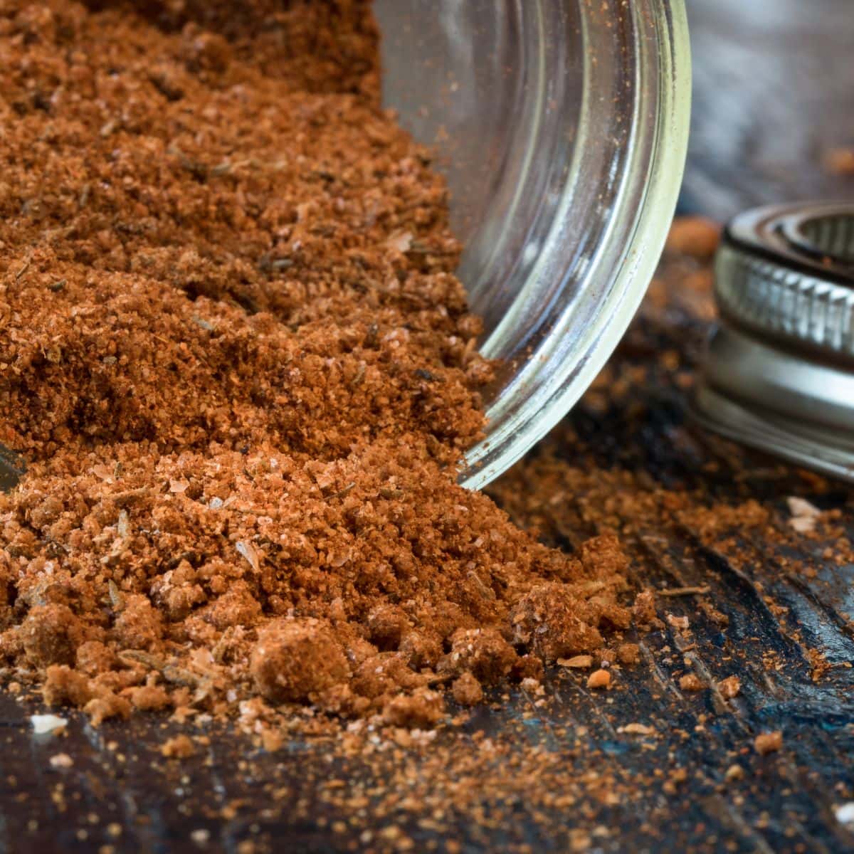 Steak rub spilling out of a jar that's tipped over.