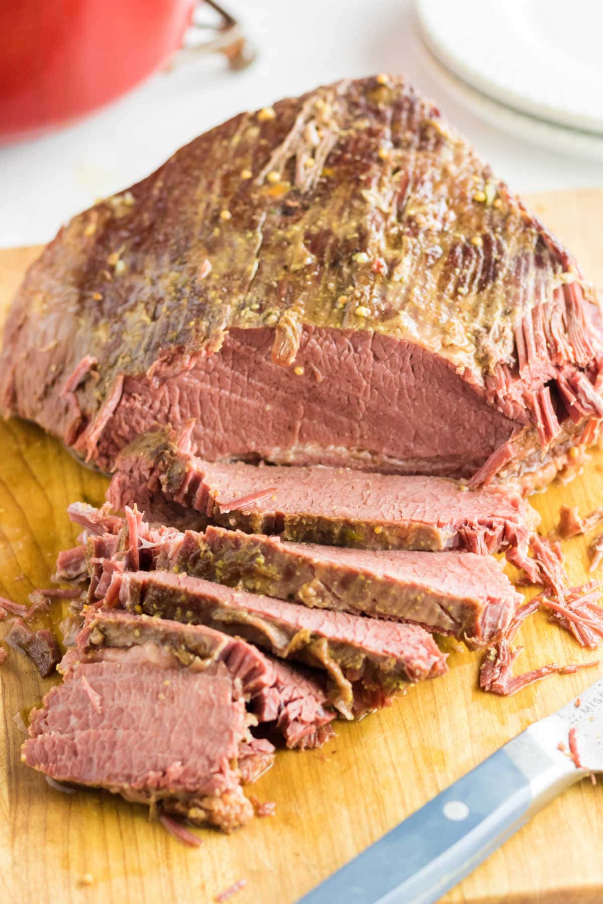 Finished corned beef brisket being sliced on a cutting board.