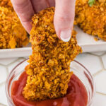 Closeup of a chicken tender being dipped in ketchup with a title text overaly for Pinterest