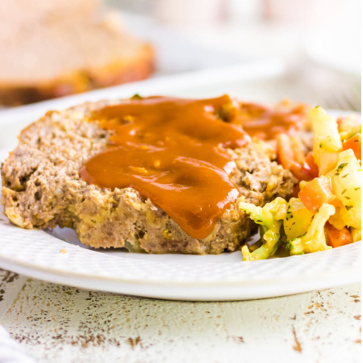 Closeup of a slice of meatloaf dripping with sauce.