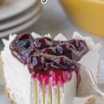 A slice of blueberry cheesecake with a bite removed and text overlay for Pinterest.