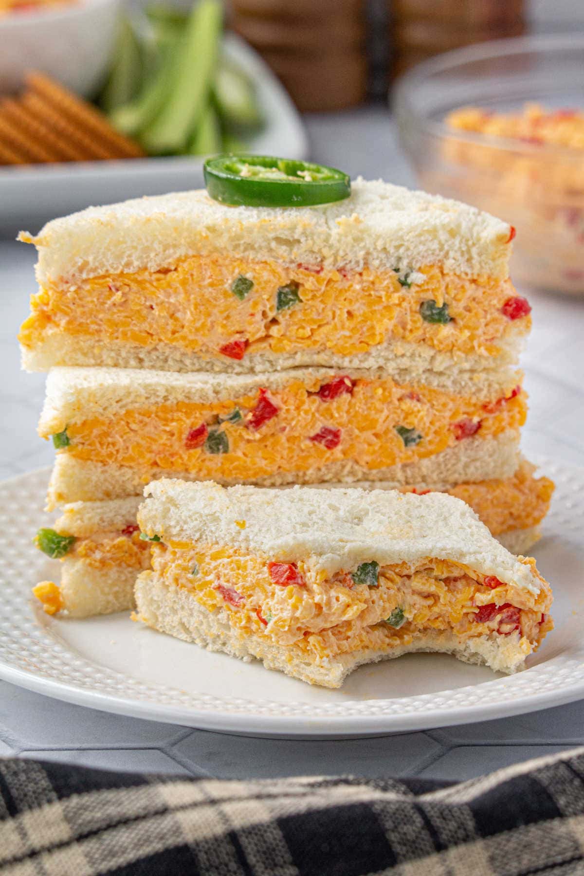 A stack of pimento cheese sandwiches on white bread.