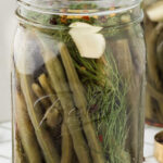 A jar of pickled green beans on a countertop with a title text overlay for Pinterest.