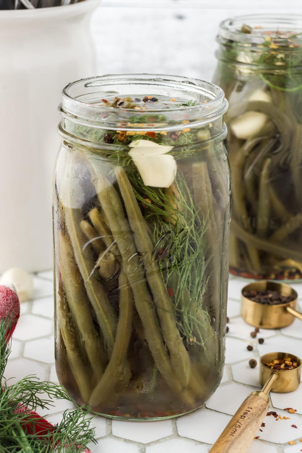 A glass jar with pickled green beans inside.