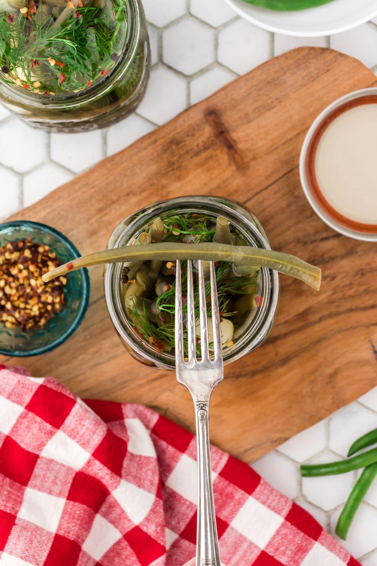 A fork removing a pickled green beans from the jar.