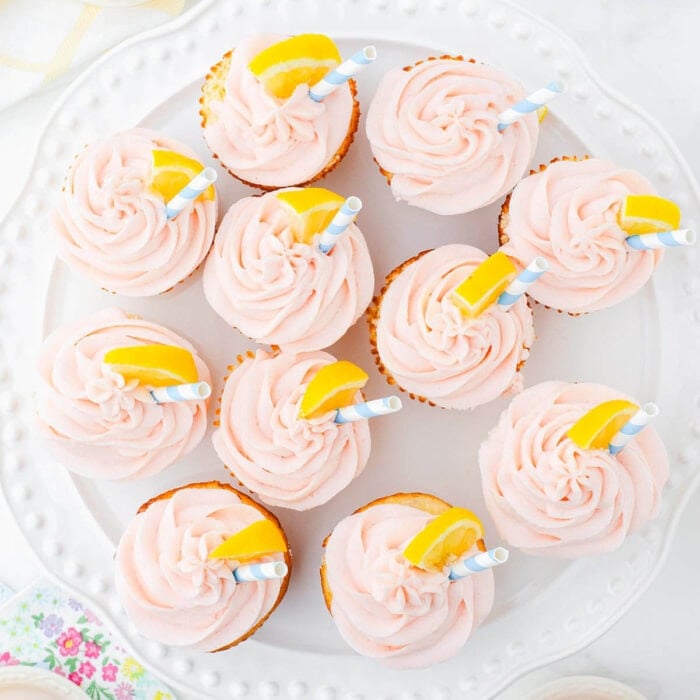 Overhead view of pink frosted cupcakes with a lemon wedge on top.