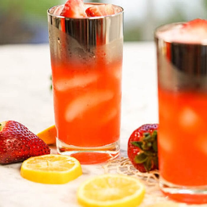 Two glasses of pink lemonade on a table.