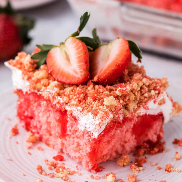 A square of pink cake with strawberries on top.