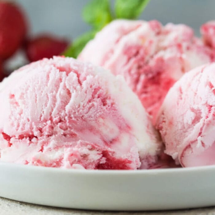 Scoops of strawberry ice cream on a plate.