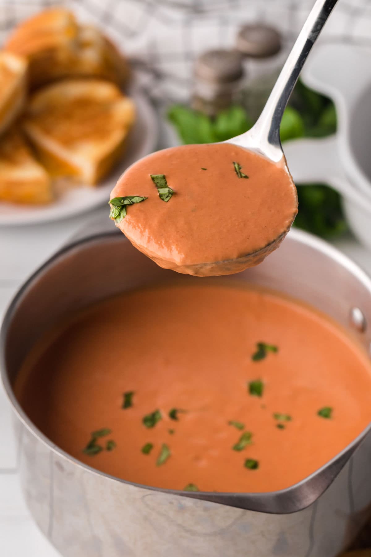 A spoonful of tomato soup being removed from the pot.