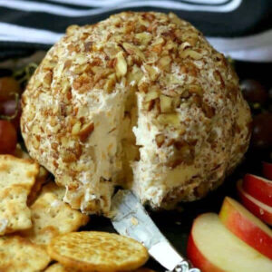 A cheese ball covered in pecans on a table.