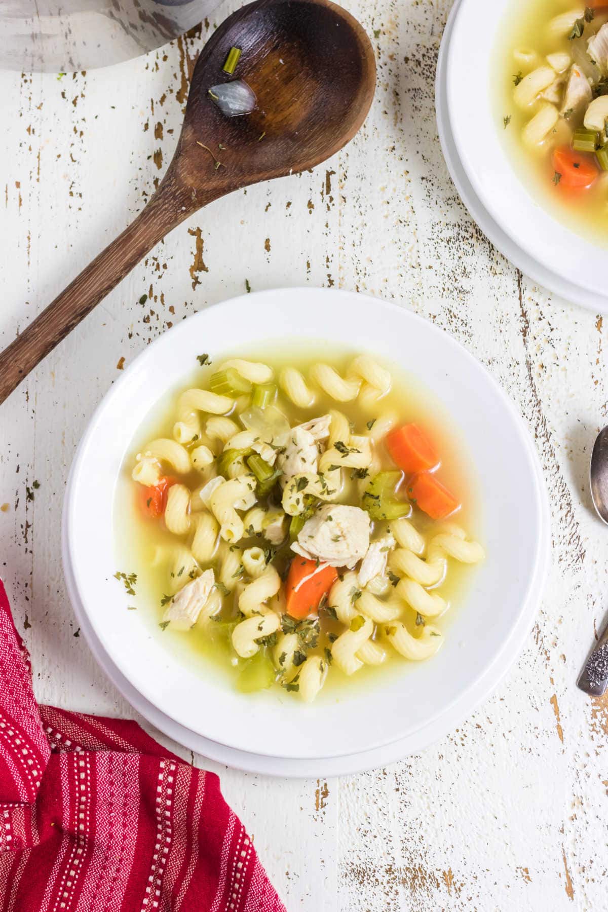 Overhead view of chicken soup with a wooden serving spoon.