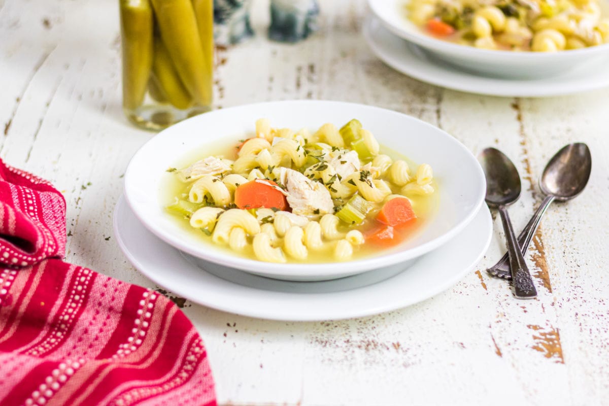 Two bowls of soup cooling on a white wooden counter.