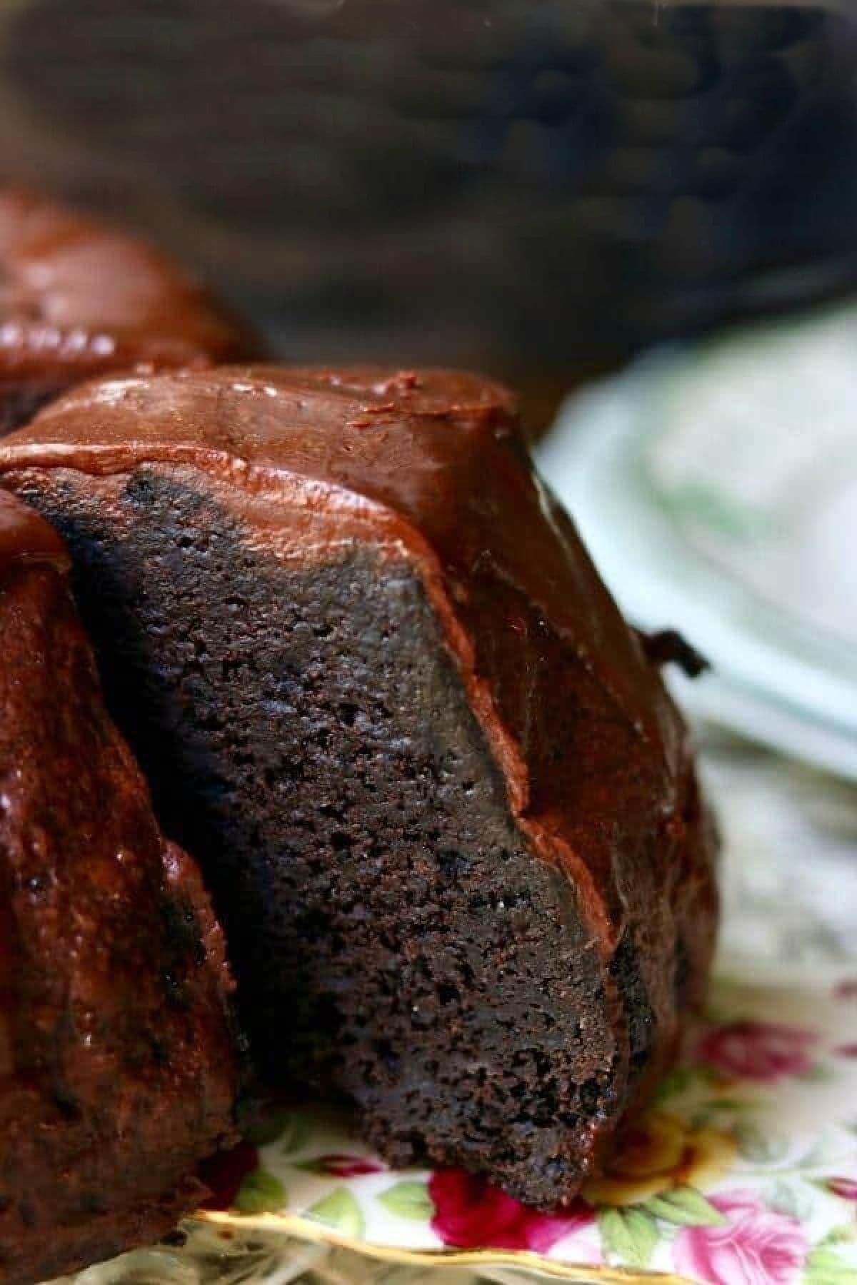 A slice being removed from a chocolate bundt cake with chocolate frosting.