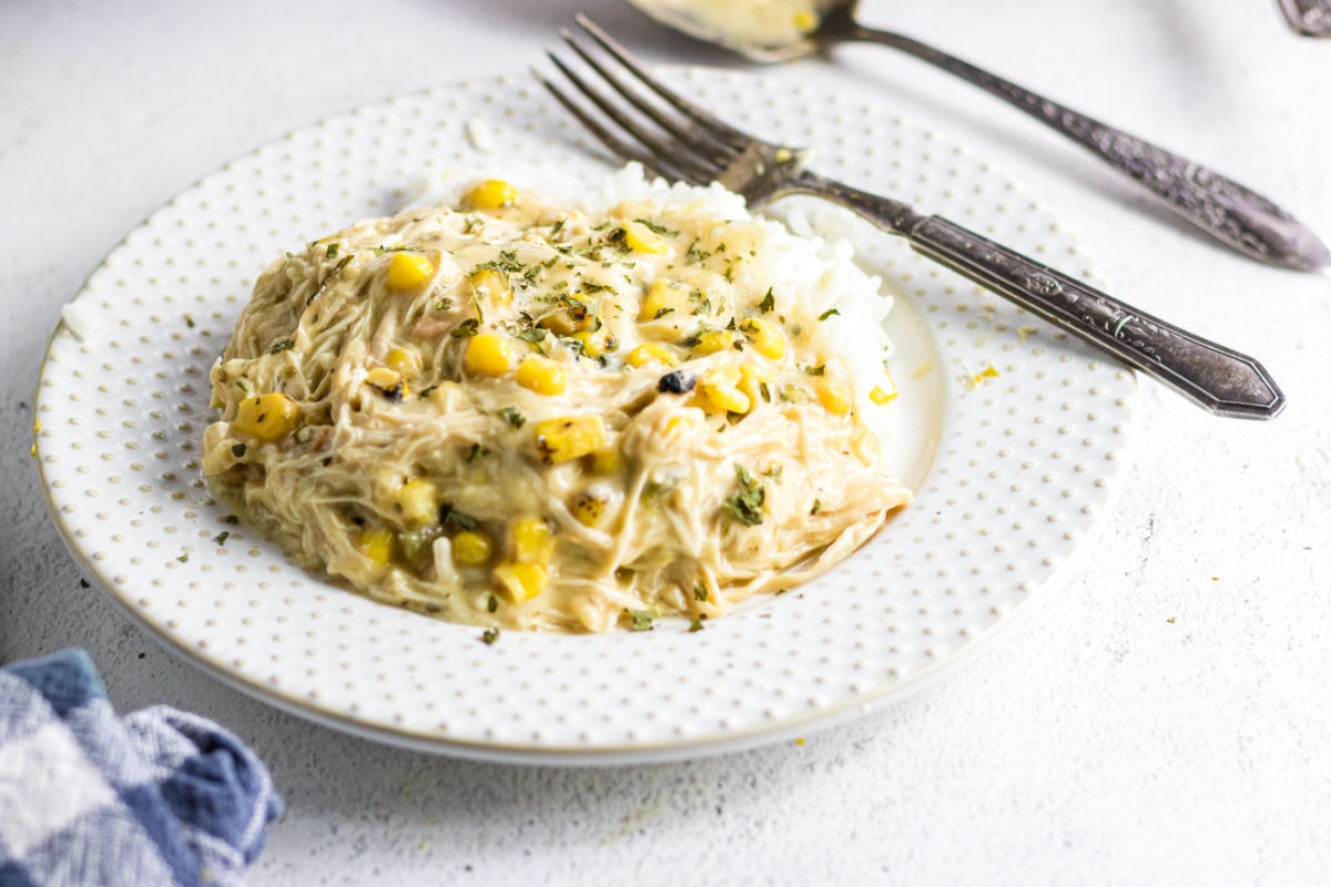 A mound of rice covered with this creamy slow cooker chicken on a white plate.