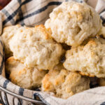 Closeup of drop biscuits in a basket with text overlay for Pinterest.