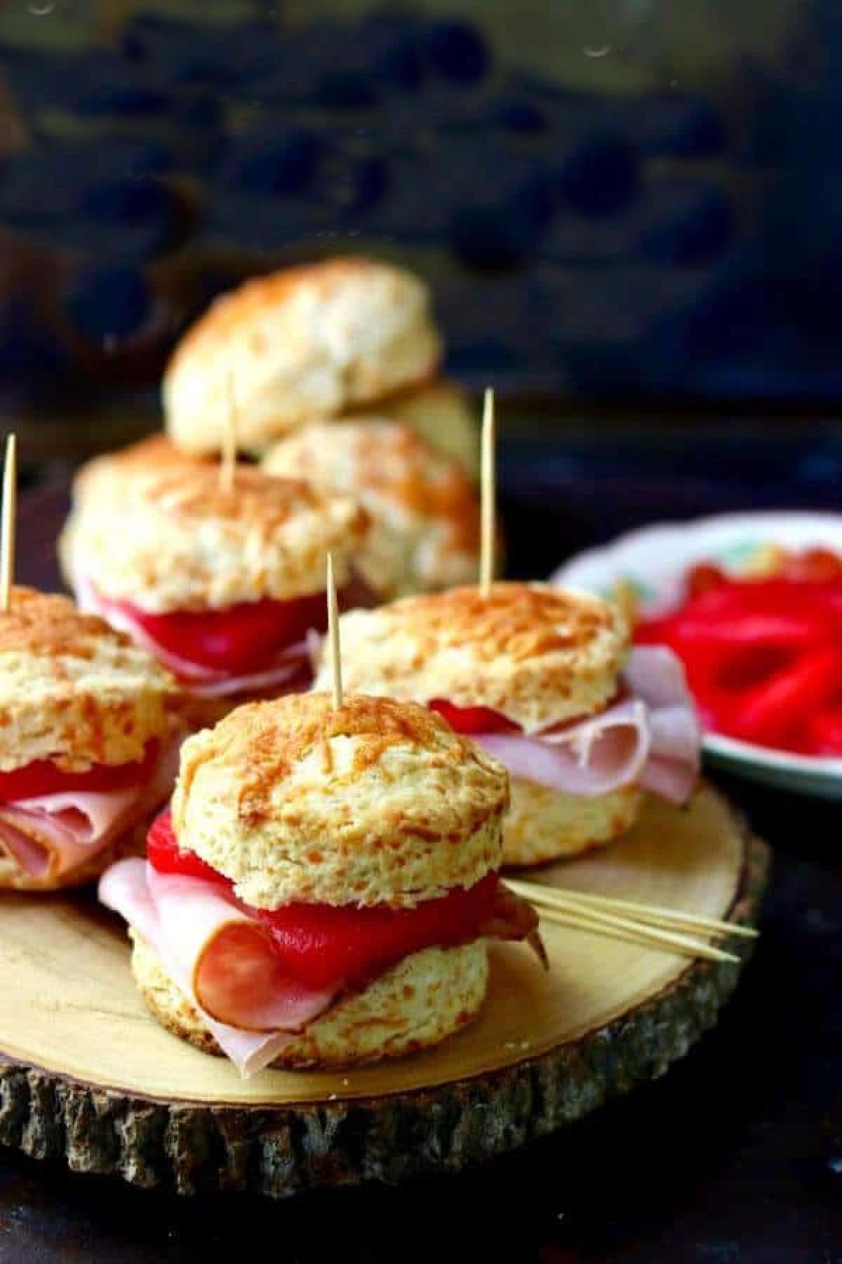 Ham and cinnamon apples on biscuits stacked on a plate.