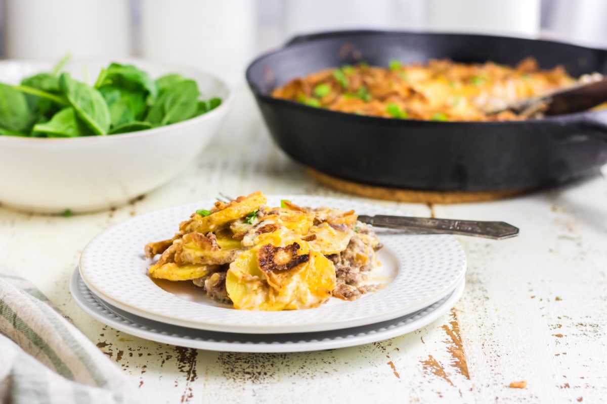 A plate of casserole on the table with a salad.