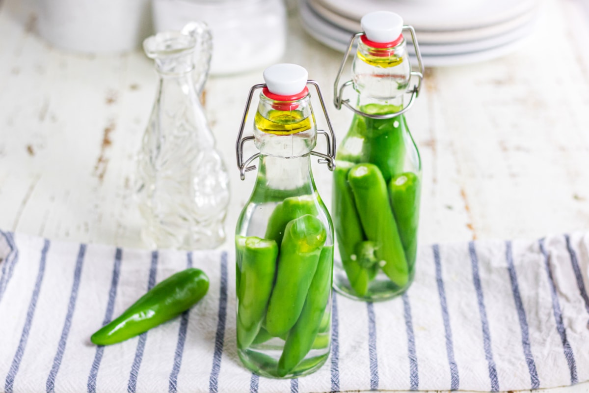 Two bottles of hot pepper vinegar on a blue striped towel.