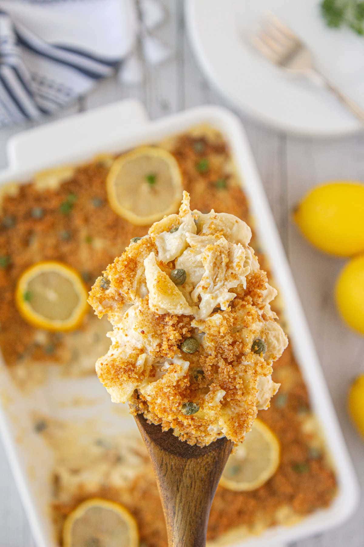 A serving of chicken piccata casserole being lifted from the casserole dish.