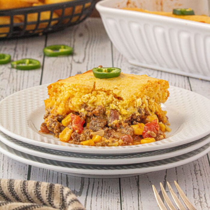The casserole on a white plate showing the layers of beef, vegetables, and cornbread.