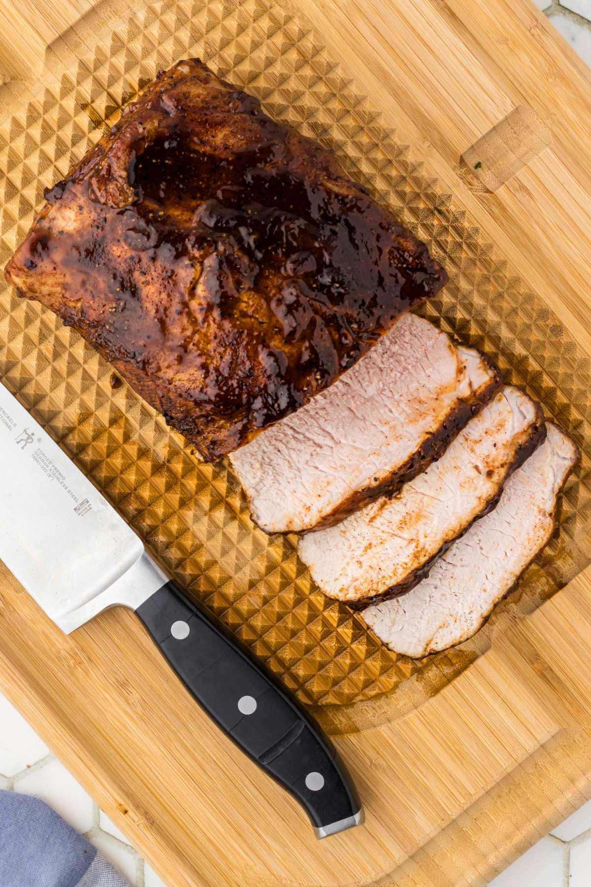 Overhead view of the pork loin sliced on a cutting board with a knife next to it.