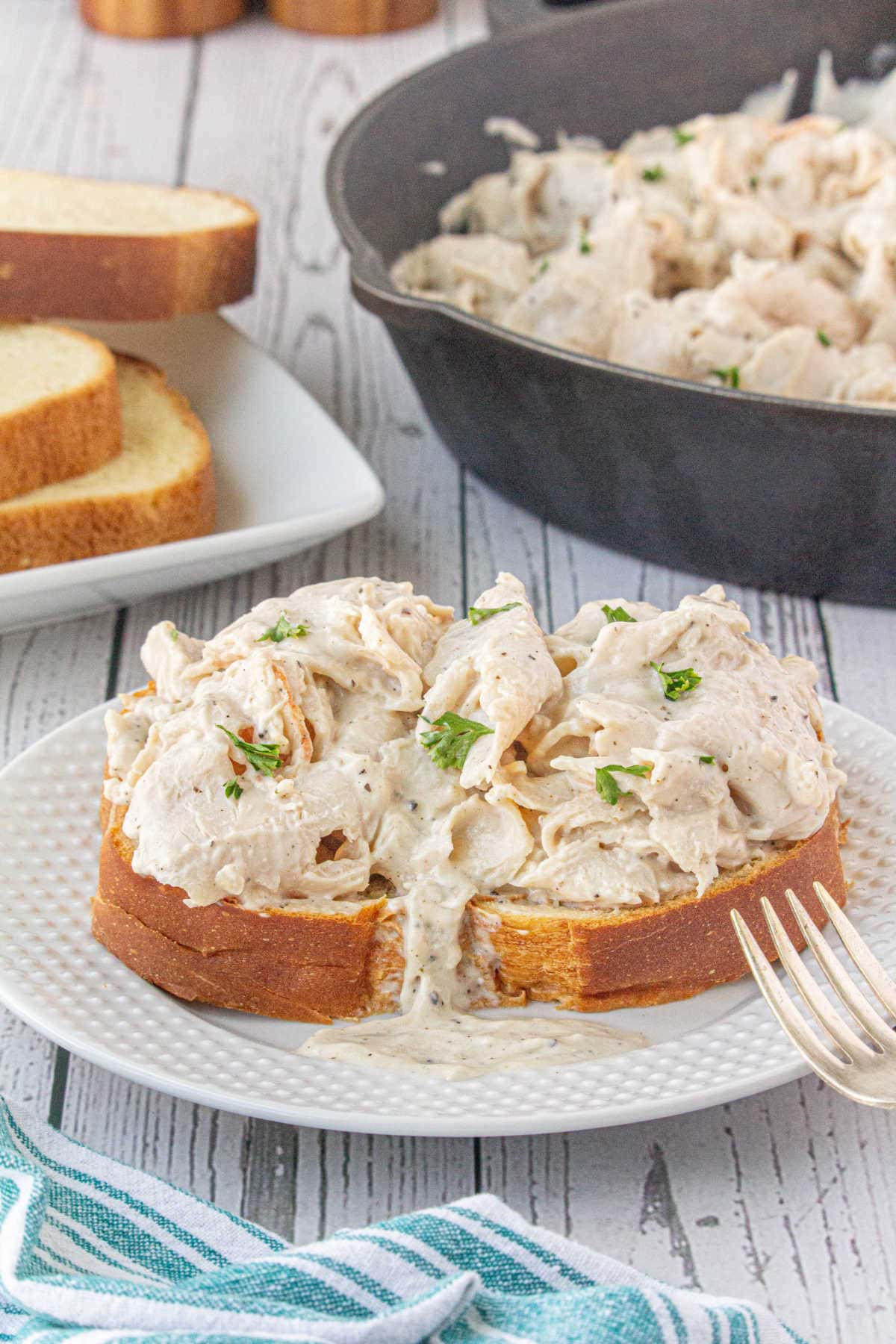 The creamed turkey spooned over a slice of bread with the skillet in the background.