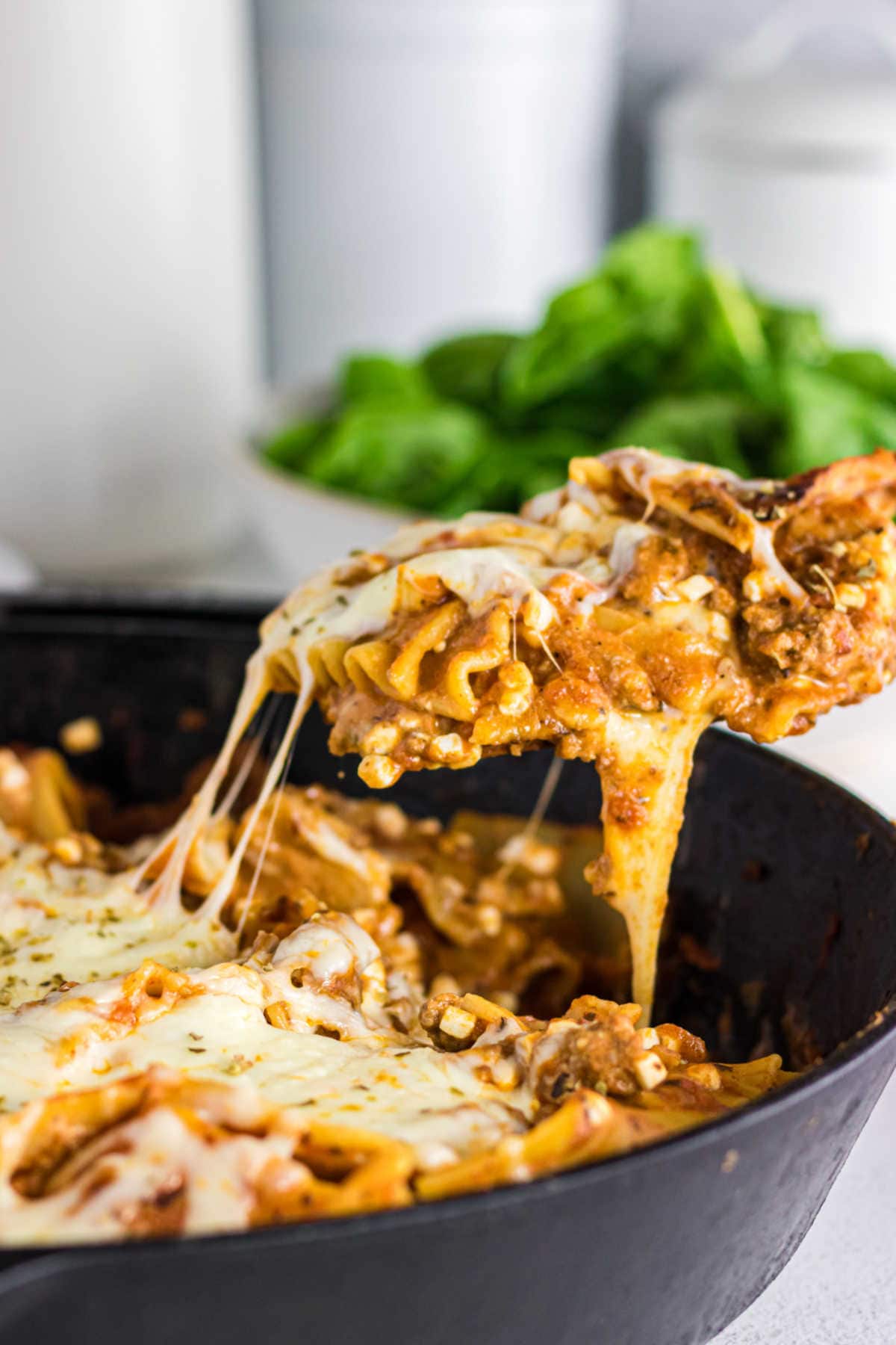 Lasagna being lifted out of the skillet to be served.