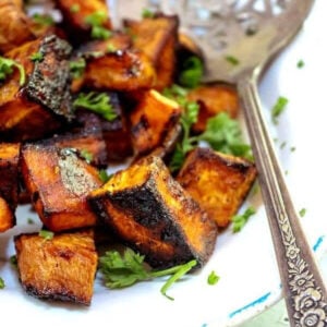 Orange sweet potato cubes with caramelized edges on a plate waiting to be served.