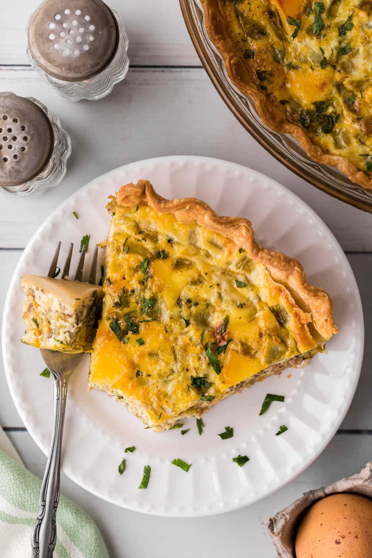 A slice of sausage quiche on a white plate.