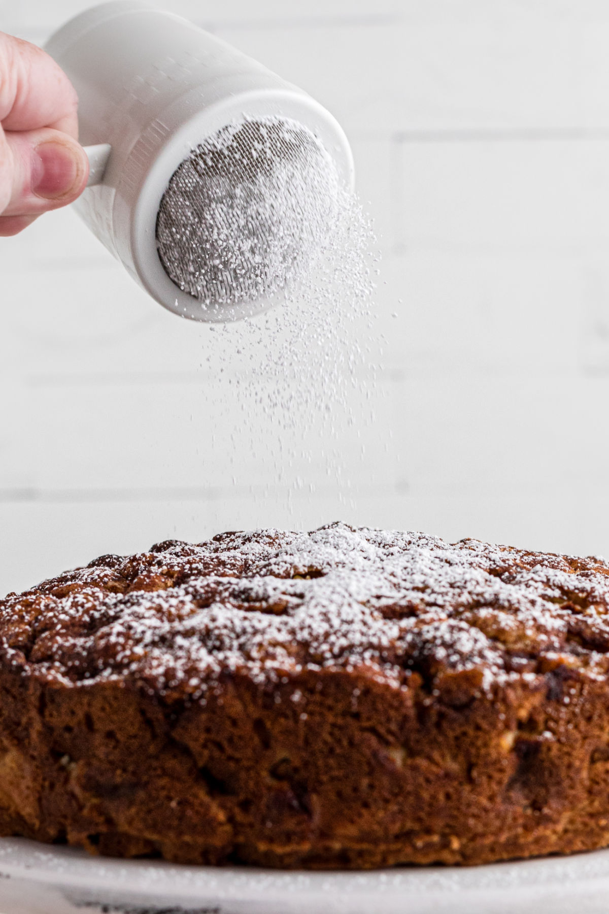 Sprinkling powdered sugar over the finished cake.