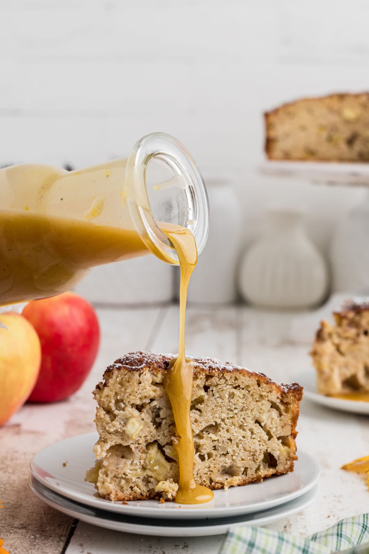 A slice of apple cake with brown butter whiskey sauce being poured over the top.