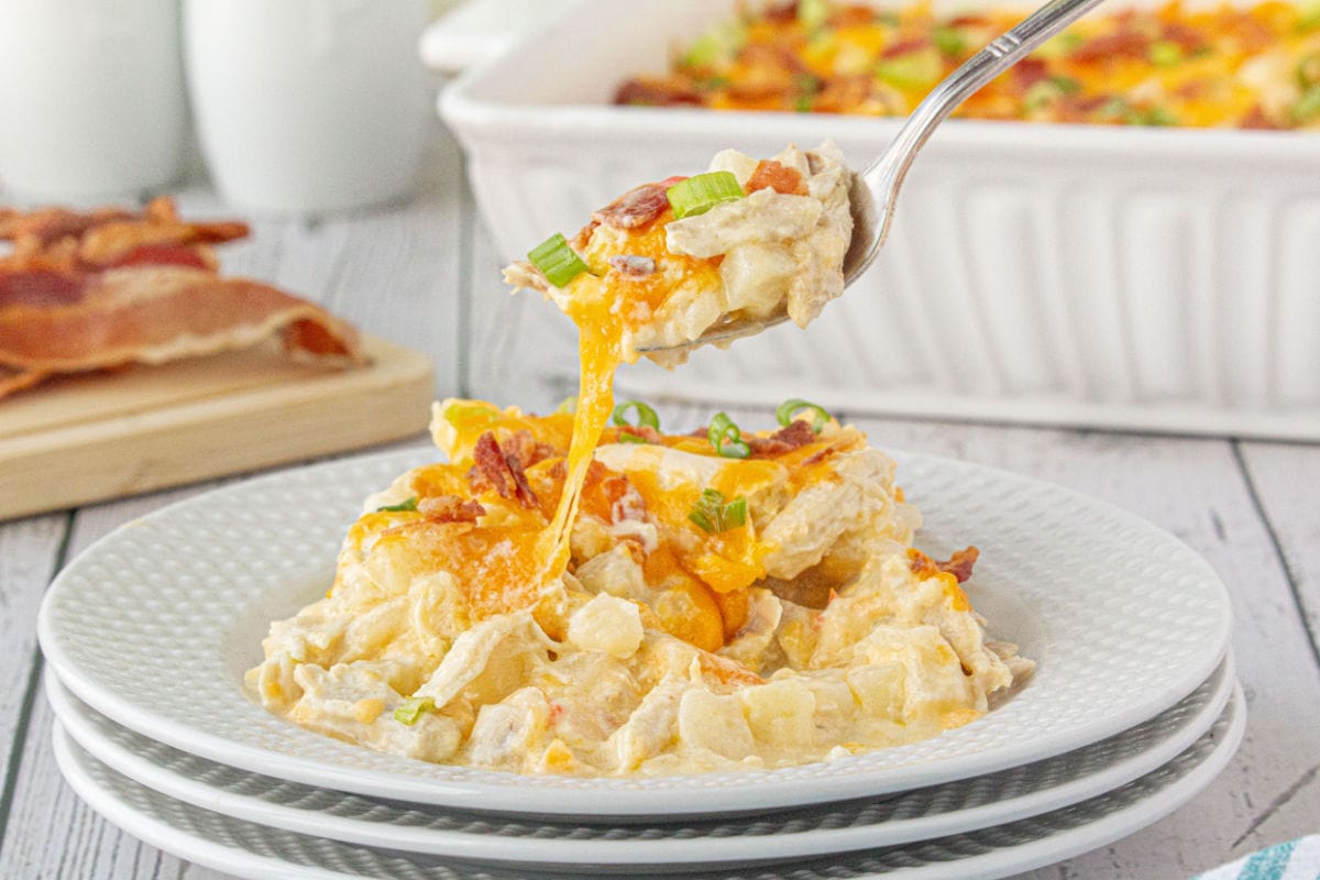 A closeup view of the cheesy casserole being lifted from the plate with a spoon.