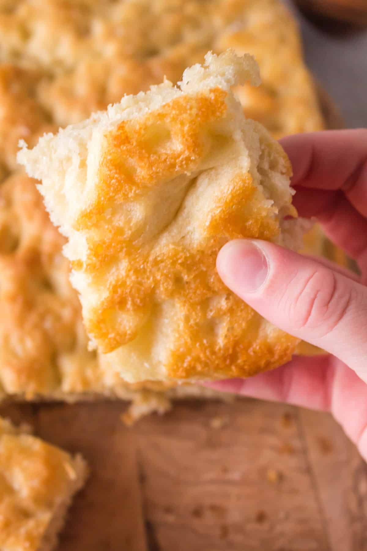 A slice of crusty Italian focaccia in someone's hand.