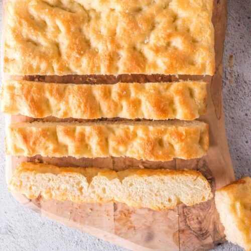 Overhead view of sliced focaccia bread on a cutting board.