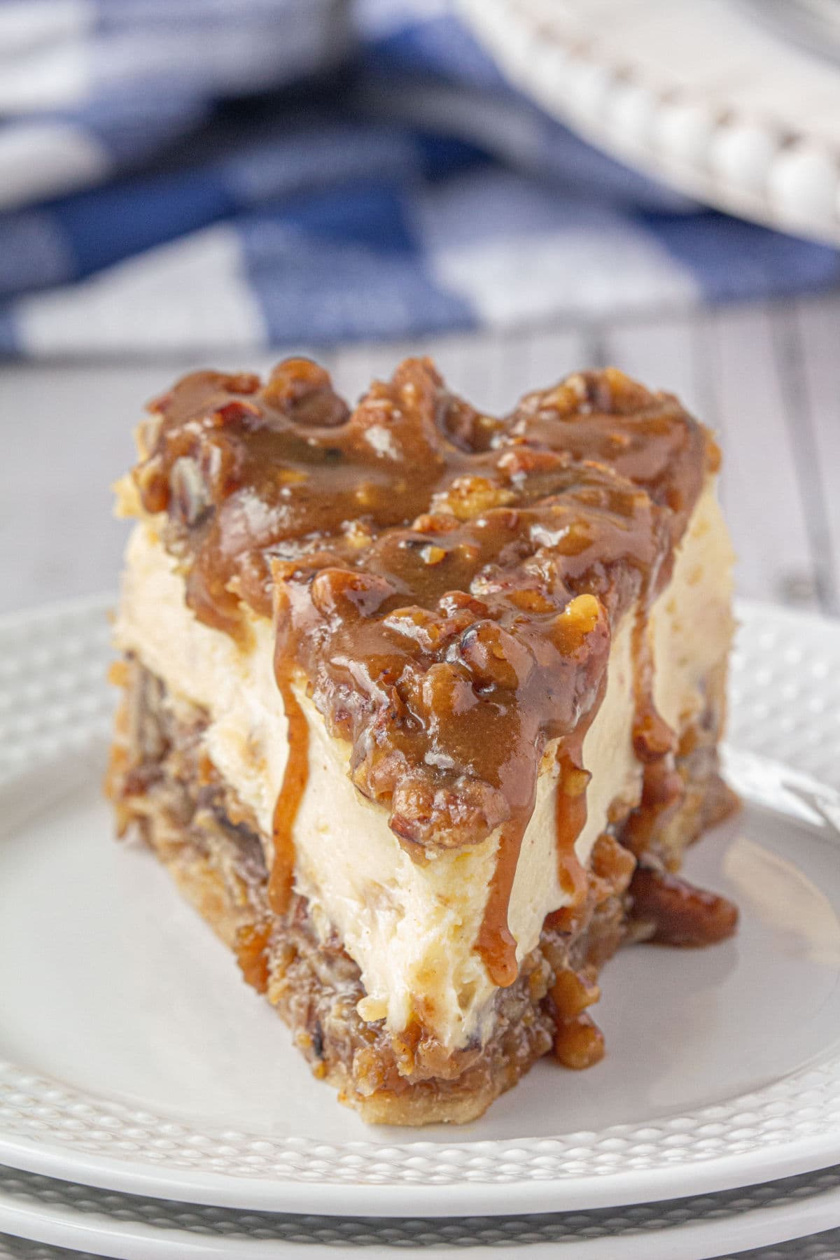 A slice of pecan pie cheesecake on a white plate.