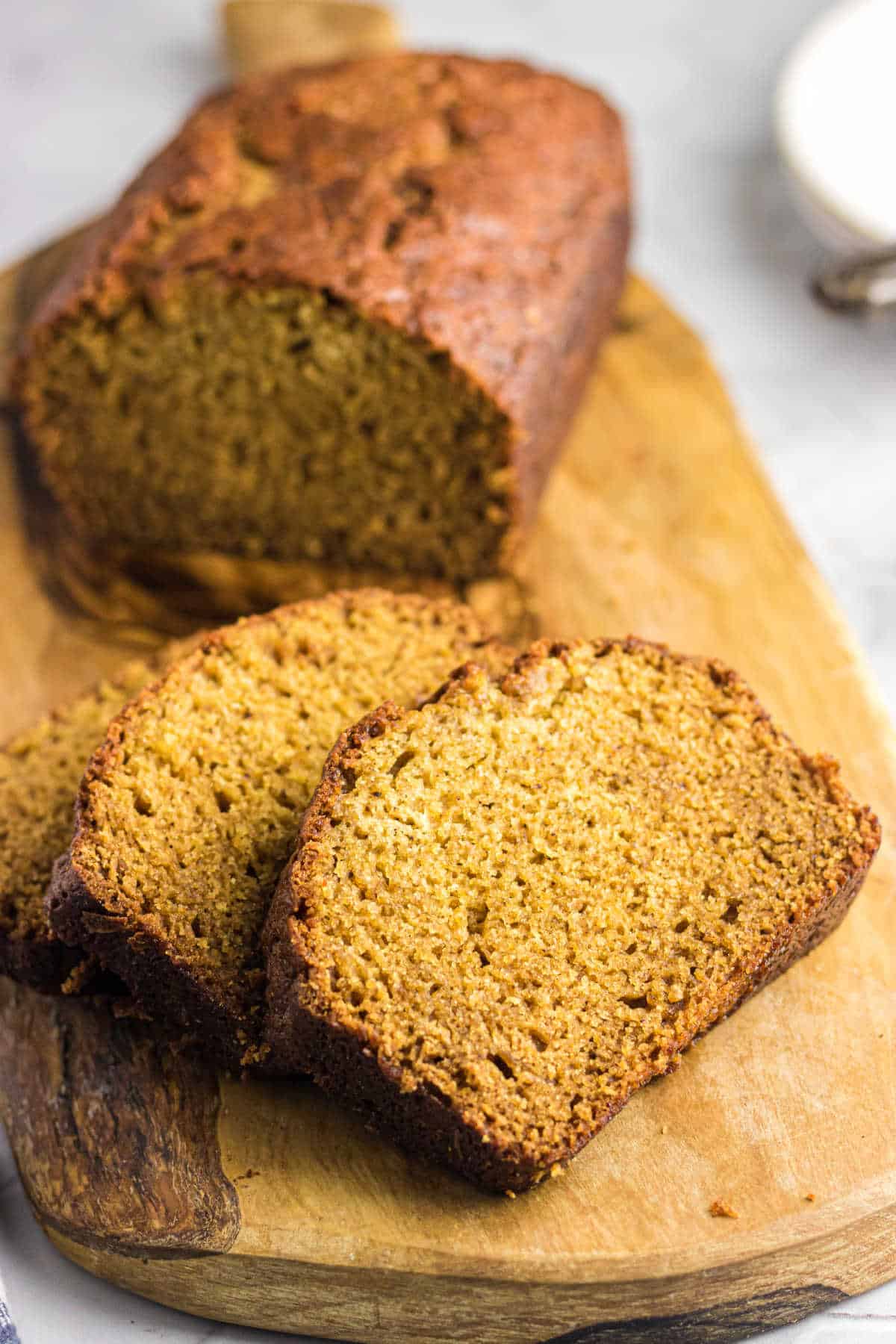 A loaf of acorn squash bread sliced on a cutting board.