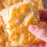 A piece of crusty white focaccia bread in someone's hand with text overlay for Pinterest.